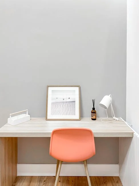 Two women dressed for work are cleaning a modern living room with a vacuum cleaner and a mop.